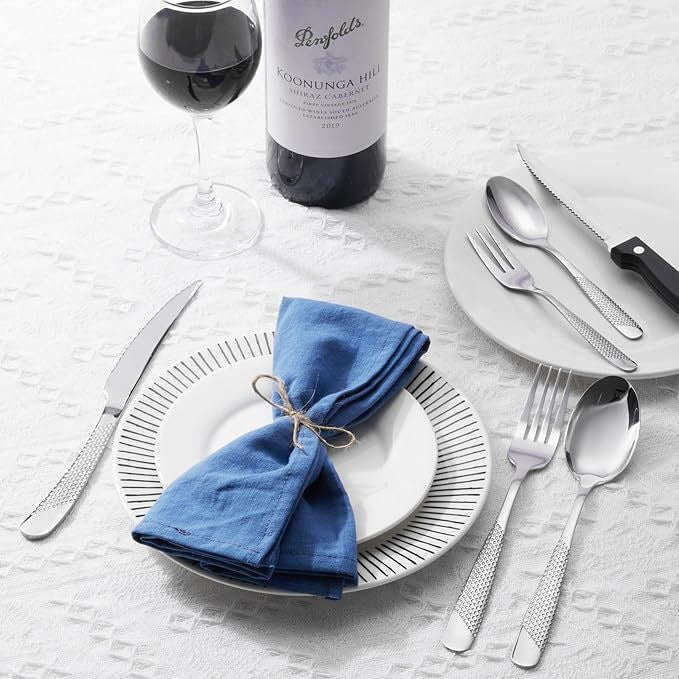 stainless steel flatware set on dining table with wine glass